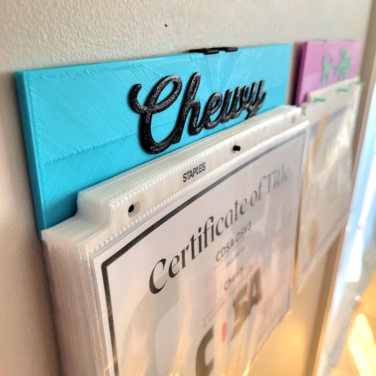 Chewy's is holding just over 30 certificates in a combo of light weight and heavy weight paper, using wall plugs and screws to mount. If you are using double-sided tape or other odd ways to mount it, the weight it can hold will vary. So as a caution, we say 15 heavyweight papers max or 200 grams.